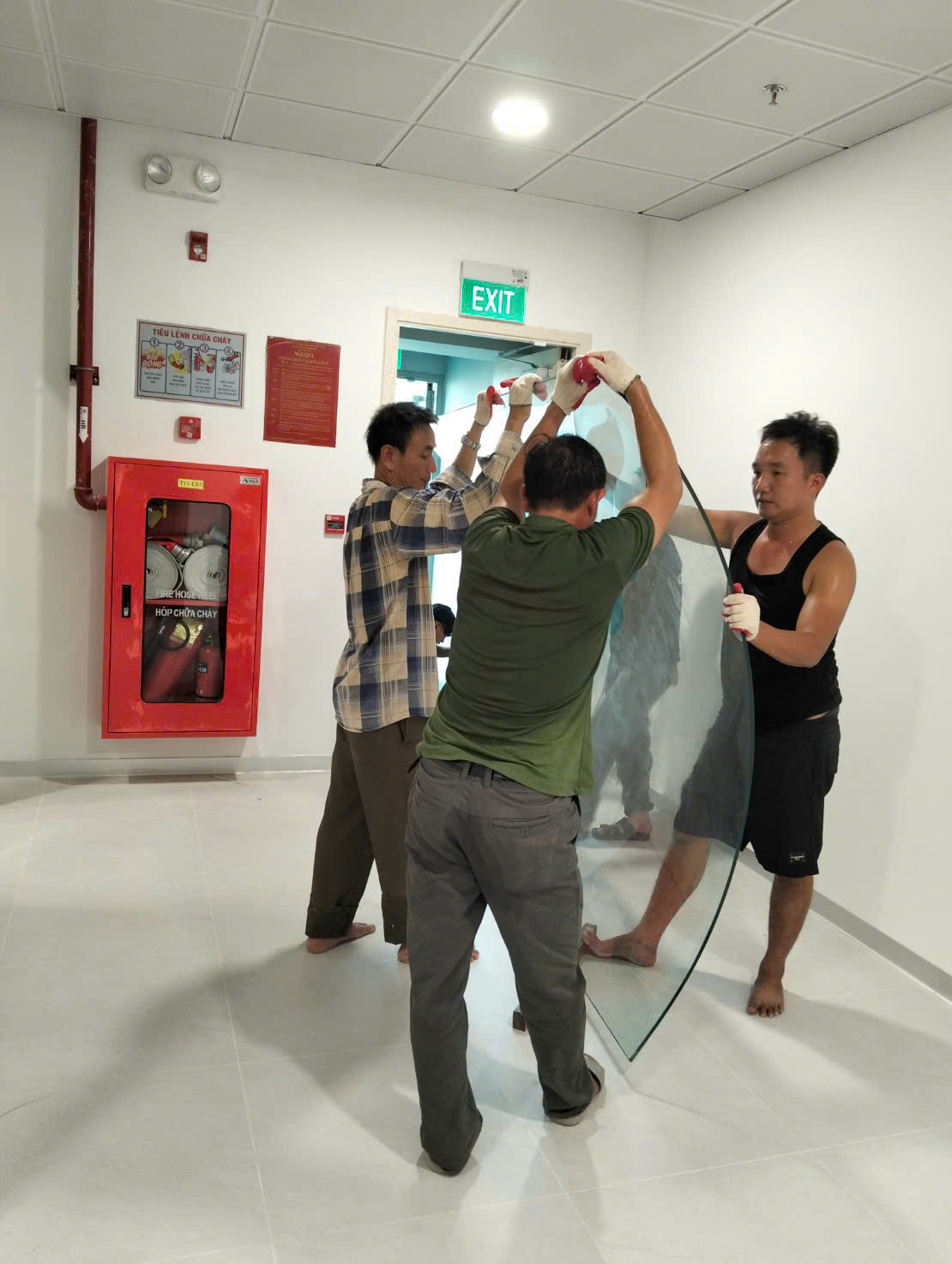 Đội thi công phối hợp nâng tấm kính lớn bên trong tòa nhà